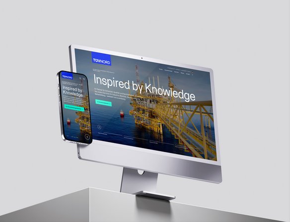 A computer screen and a smartphone display the relaunched home page of the TÜV NORD website.
