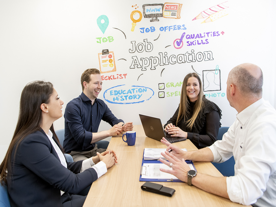 Teaser_Admin_HR_1200x800 Eine gemischte Gruppe von vier Menschen arbeitet an einem Tisch zusammen.